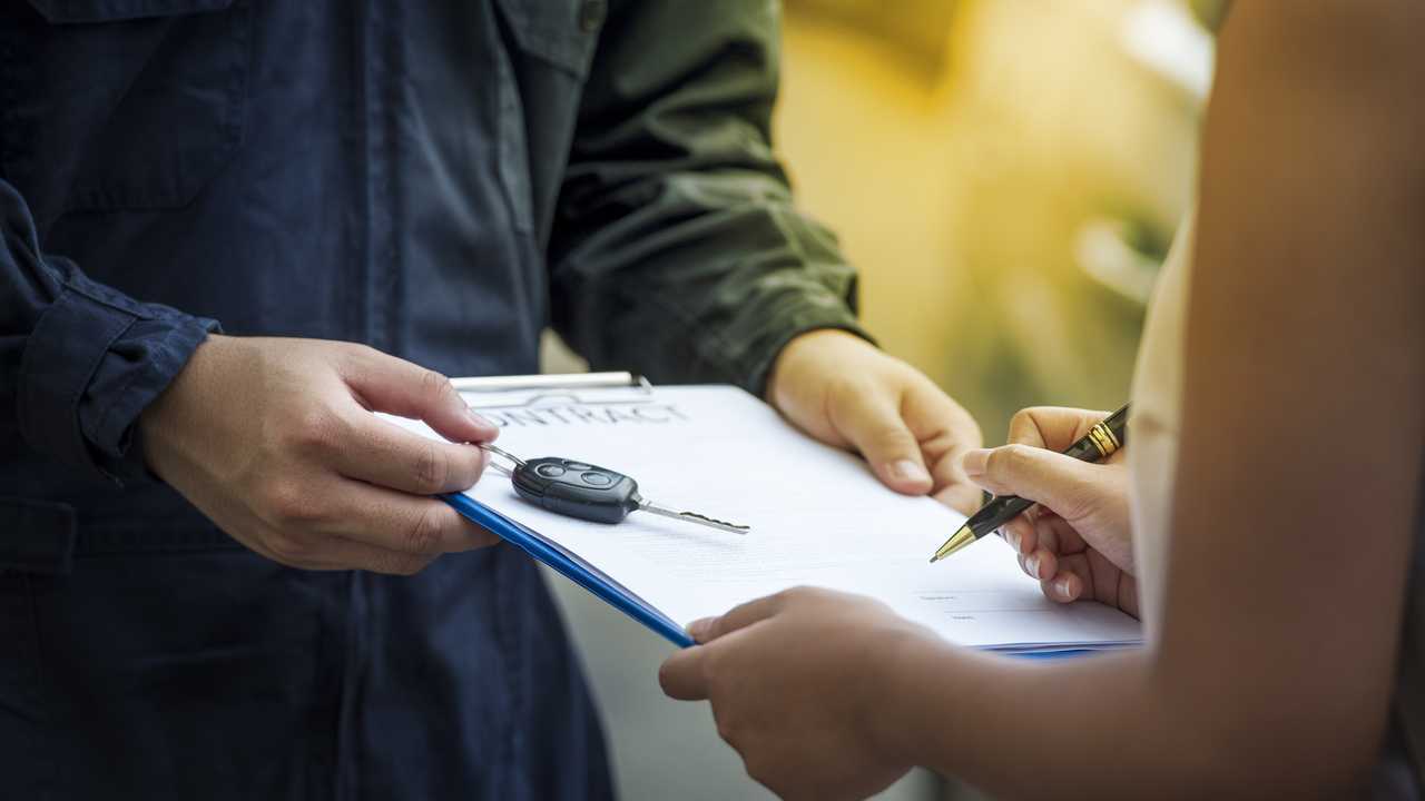 Customer signing finance contract with car salesman